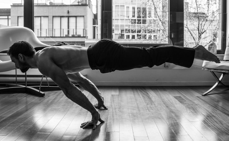 Man performing an advanced calisthenics move indoors, demonstrating strength and balance, related to calisthenics workout equipment