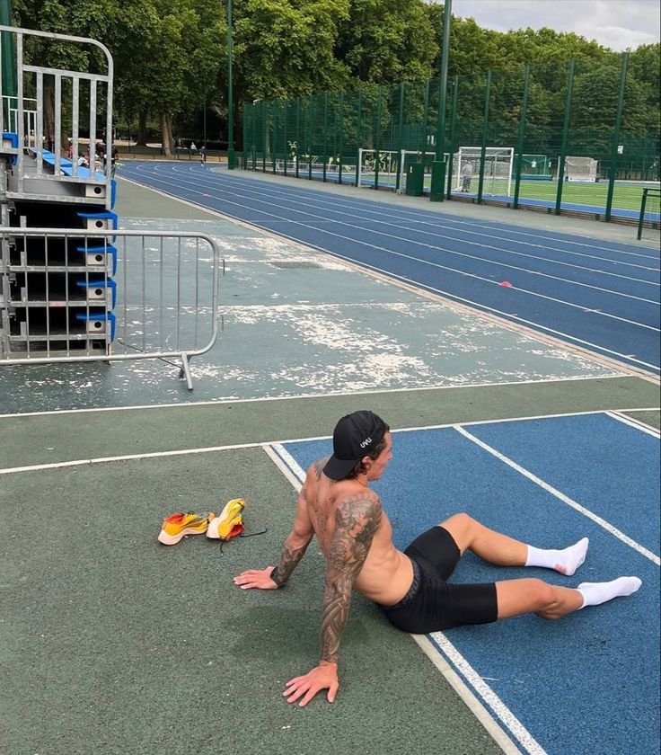 Man resting on a track after a workout session, highlighting the importance of a calisthenics workout plan for beginners.