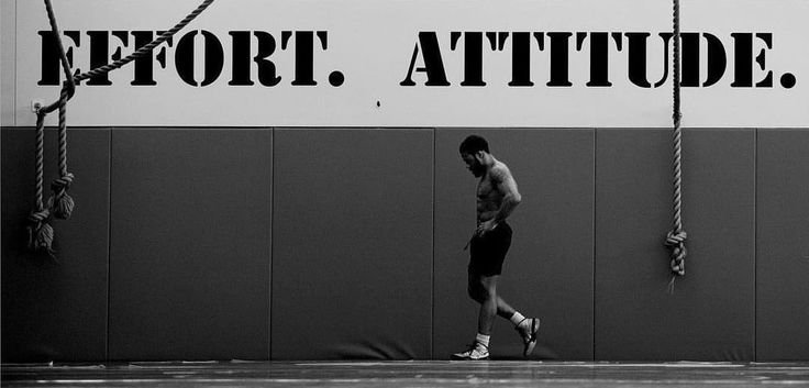 A determined athlete walking past a gym wall with the words 'Effort. Attitude.', highlighting the importance of consistency in workouts for fitness success.