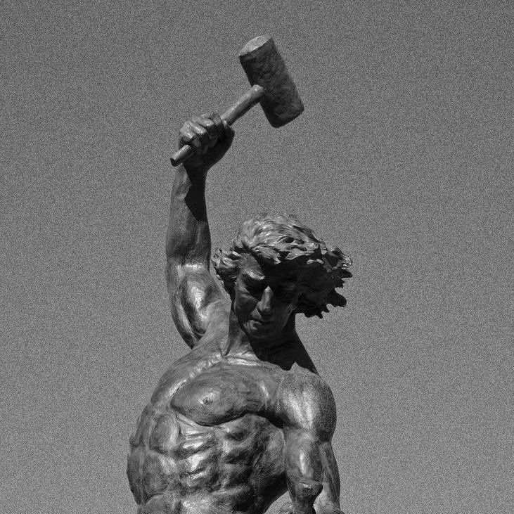 A statue of a man holding a hammer, symbolizing strength in the context of calisthenics transformation.