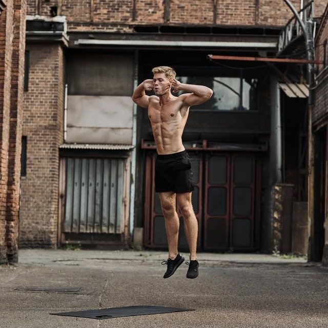 Shirtless man jumping in the air, demonstrating burpees exercise benefits