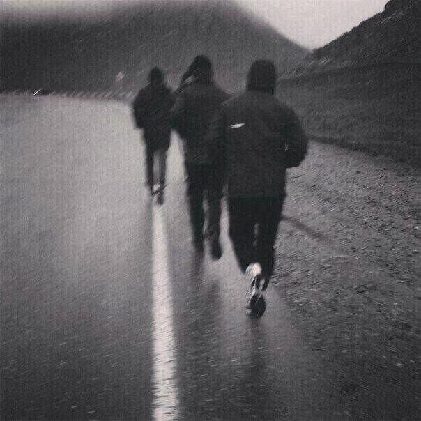 Three people jogging on a road in a mountainous area, dressed in jackets. This image accompanies the article 'Best Outdoor Workout Routine For Minimal Time and Equipment' to illustrate an effective outdoor exercise.