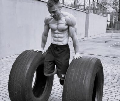 Muscular man performing calisthenics exercise with large tires, demonstrating the principle of quality over quantity in exercise through focused, controlled movements.